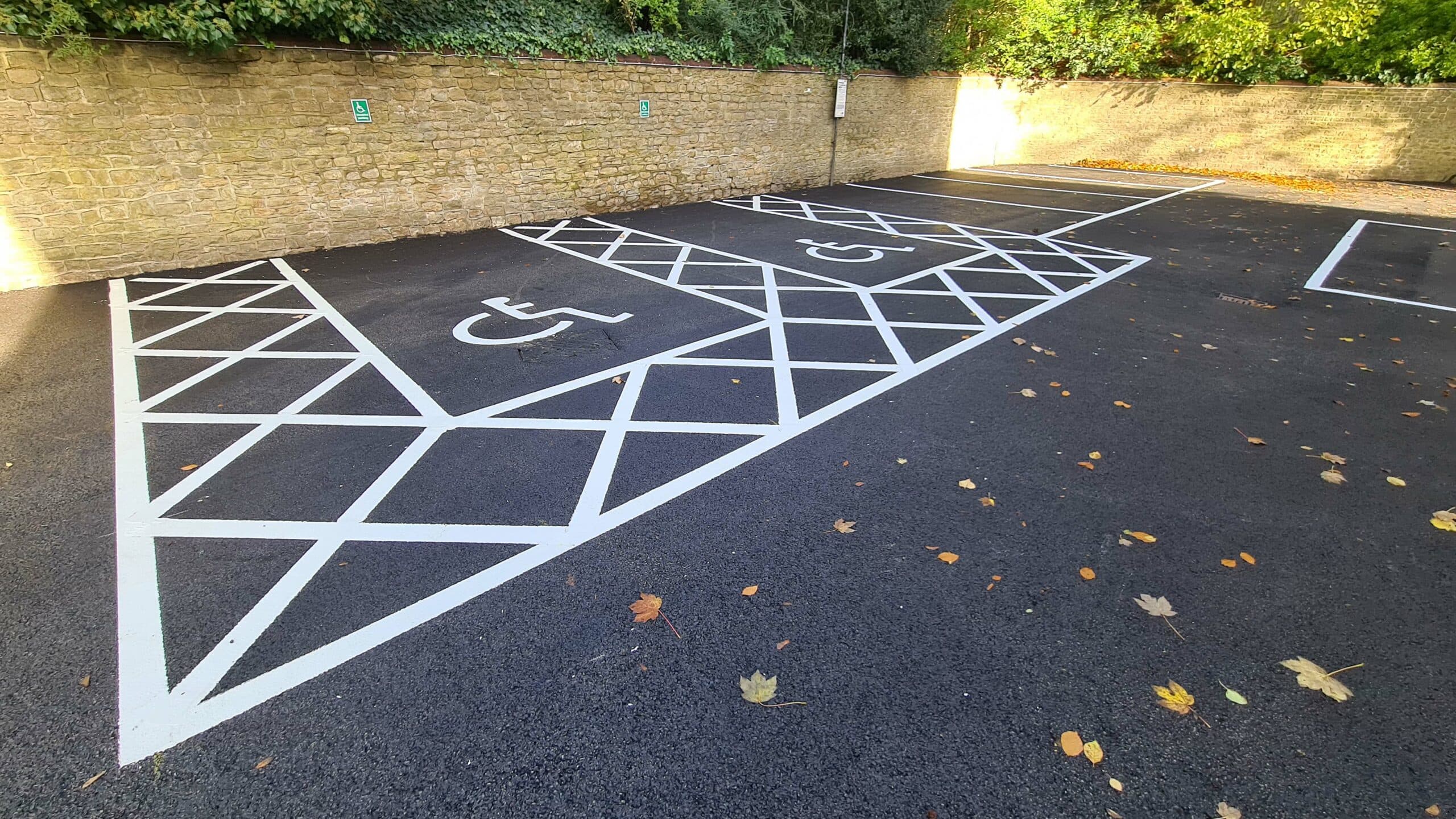 Fresh white line marking on newly sealed black asphalt disabled parking bays